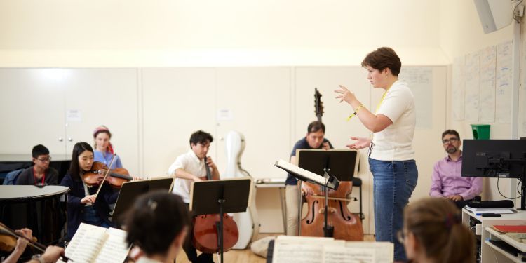 Image of person conducting a string ensemble