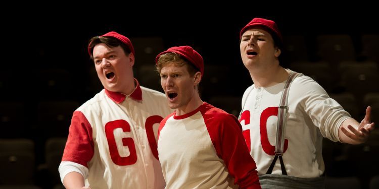 Three male opera students singing, dressed is baseball outfits as part of Our Town Opera in 2022