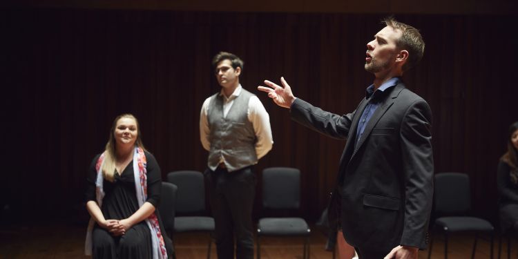 Singer performing in front of a seated woman and a standing man