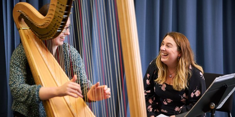 Postgraduate teaching a male student the harp