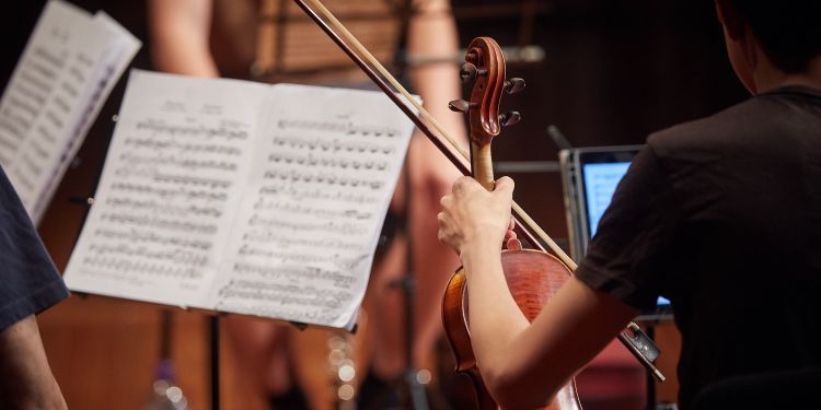 Musician holding a violin in front of a music score
