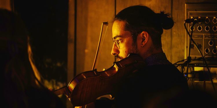 Student playing the violin in dim orange light