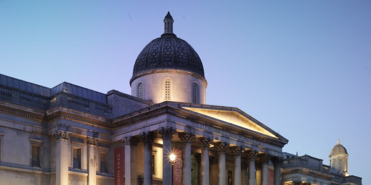 White building with pillars across the entrance and domed structure in the middle