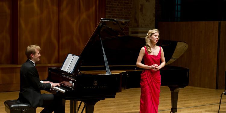 Singer in red dress accompanied by a pianist