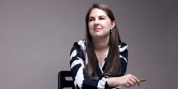 Karen Ni Bhroin conductor, sat in chair holding baton