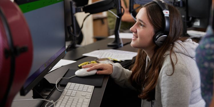 Short Course participant sits at a desk wearing headphones 