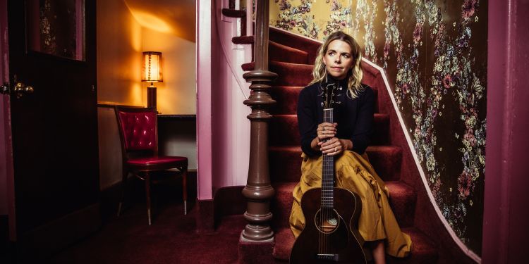 Aoife O'Donovan sat on staircase holding a guitar