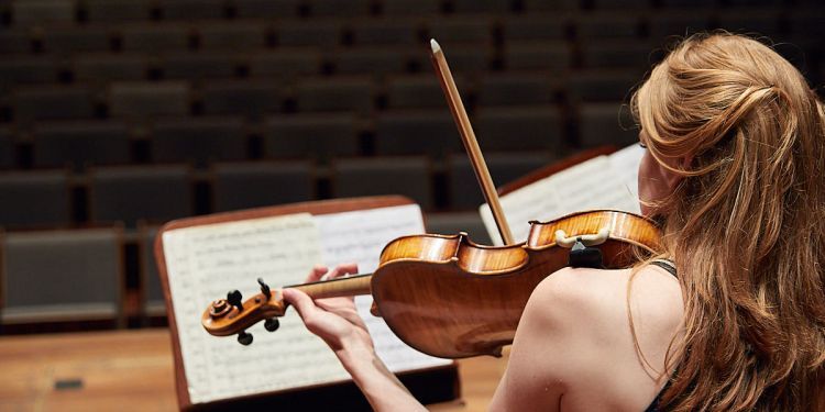 Violinist performing behind music stand with score visible