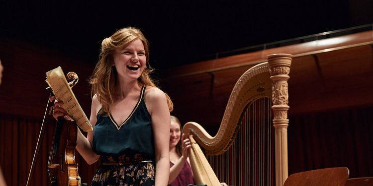 Violinist stood in front of a harp