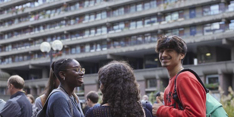 Group of three smiling students outside