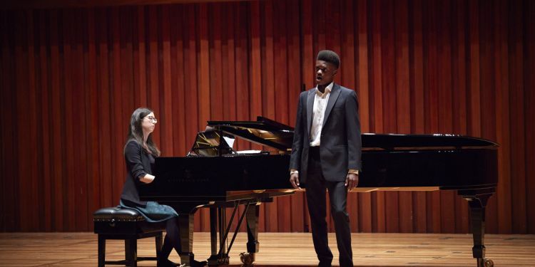 Student singing on stage with pianist