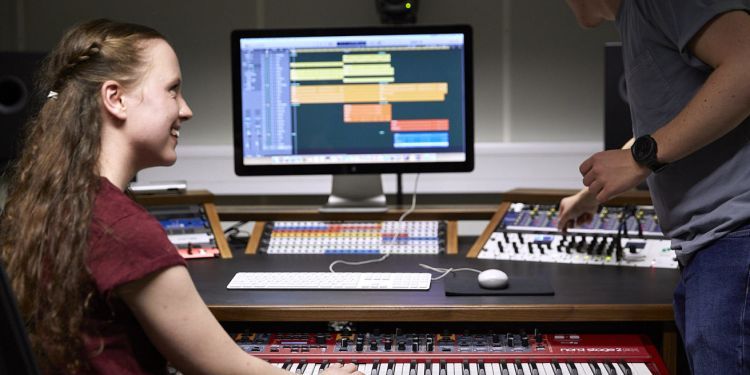 Student at a sound desk and piano 