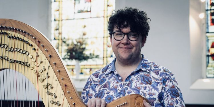 Alex Rider holding a harp smiling