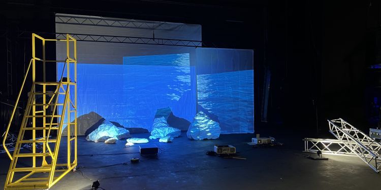An empty set with a ladder on the side and lights illuminating a stage
