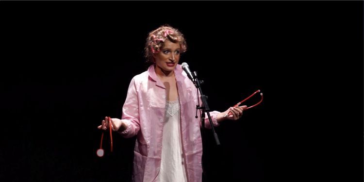 Actor on stage holding a broken stethoscope