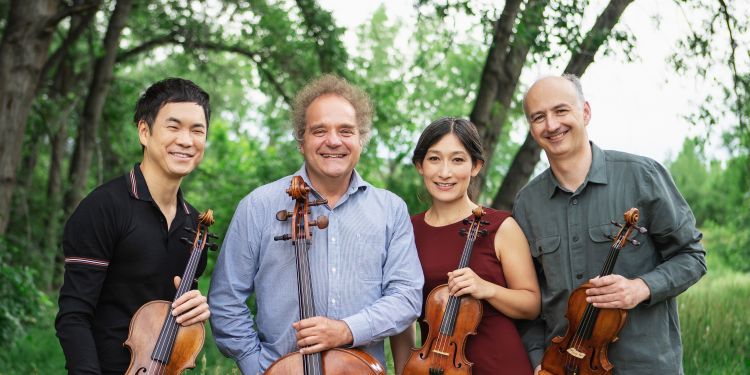 Takács Quartet posing with instruments in a field