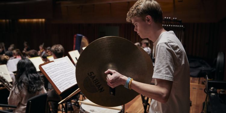 Junior student playing cymbals on stage