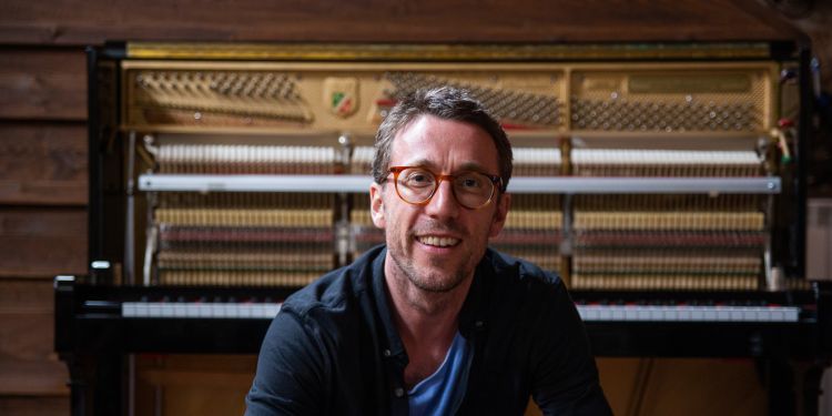 BILL LAURANCE smiling in front of a piano