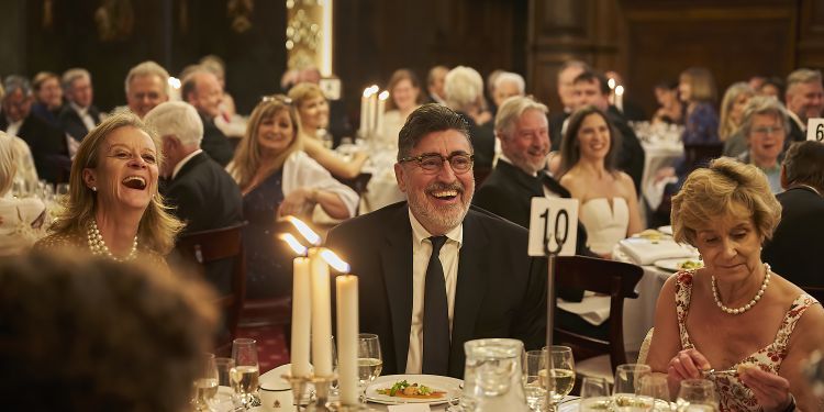 Alfred Molina and his guests sit around a table at the annual gala dinner.
