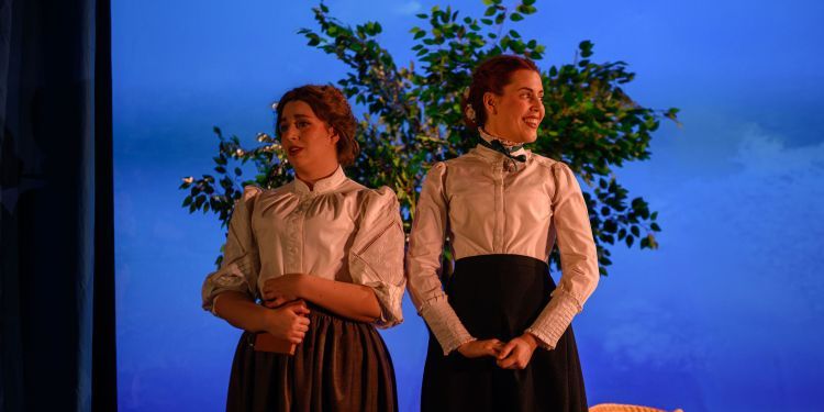 Two female singers in front of a tree