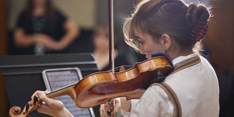 Student playing violin during a rehearsal