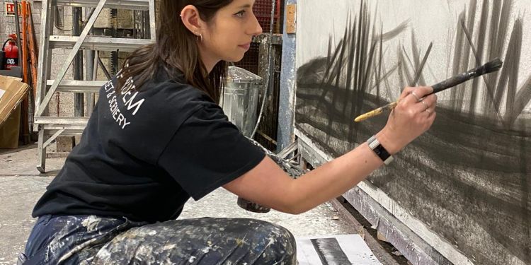 Production Arts student painting on a large canvas