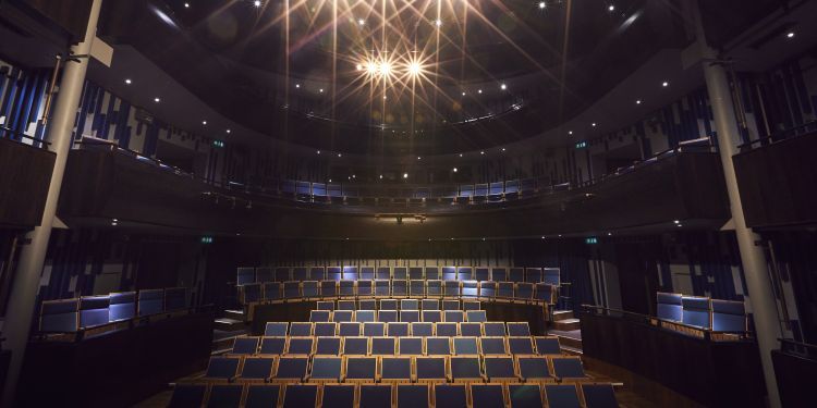 A view from the Milton Court Theatre stage facing the audience - rows of empty chairs and shining stage lights