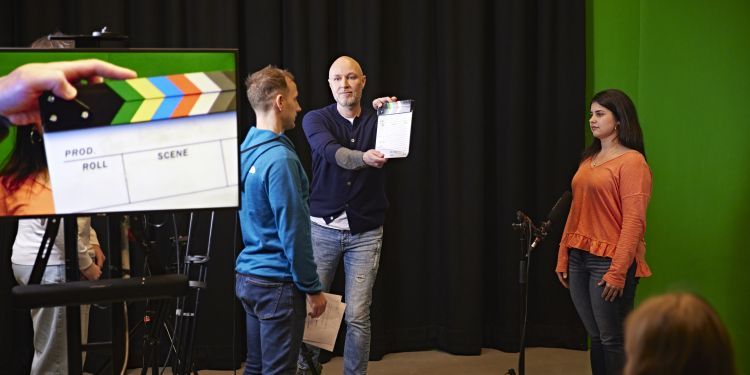 3 people standing and filming a scene 