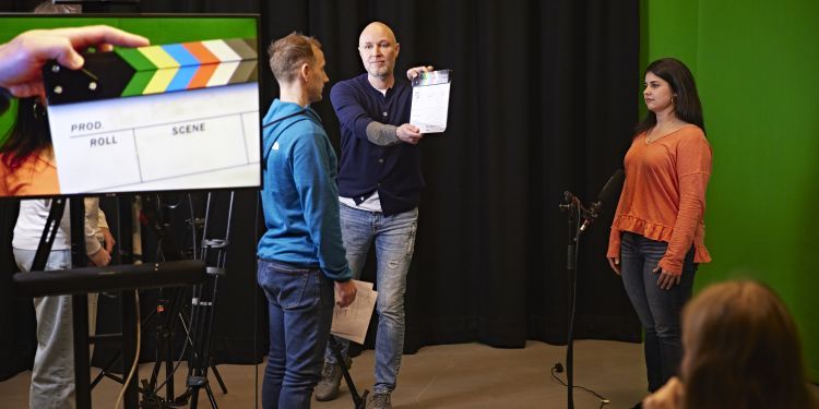 3 people standing and filming a scene 