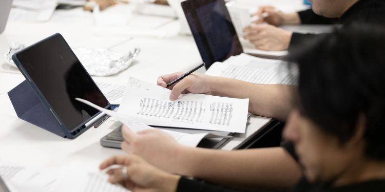 participants in classroom with manuscript paper and tablet in front of them on desk