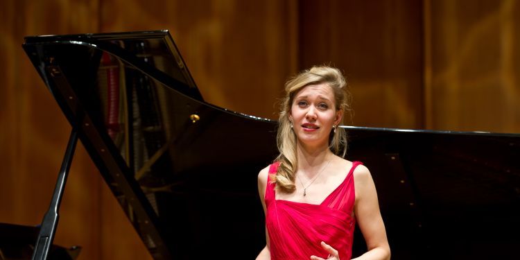 Singer performing on stage with a piano in the background