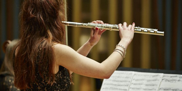 Student playing the flute standing up looking at sheet music