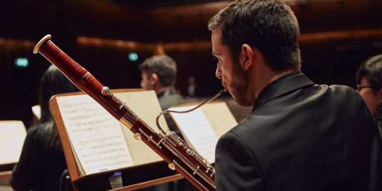 Student playing bassoon on stage looking at sheet music