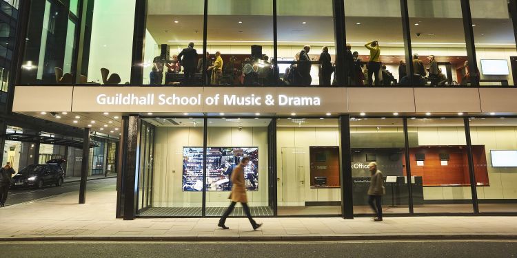 Passers by walking past Milton Court at night
