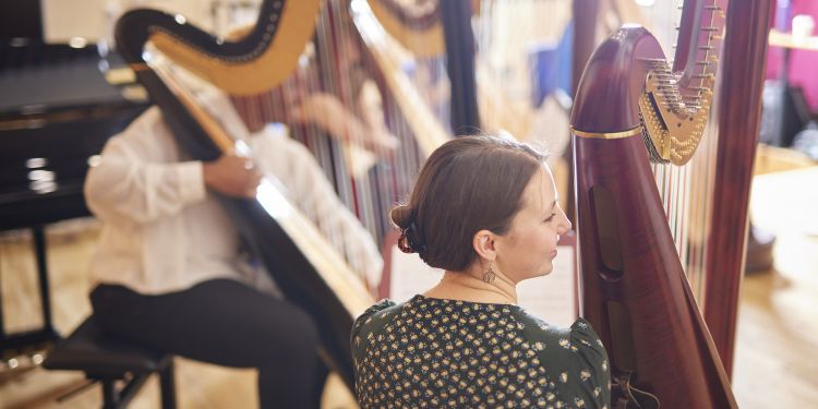Students playing the harp in a rehearsal room