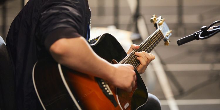 A seated guitarist looking over their shoulder