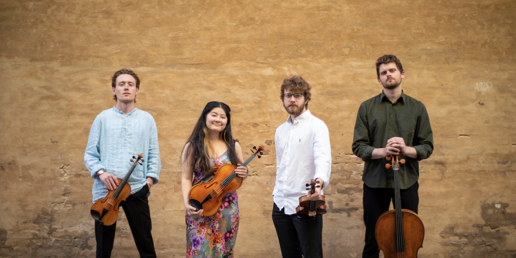 Picture of Elmore string quartet holding instruments against brick wall