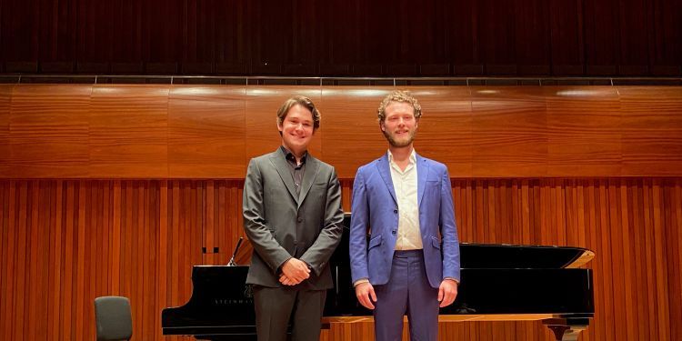 Winner of 2022 prize Jacob Harrison with Spencer Klymyshyn who was piano accompaniment standing on stage in front of a piano