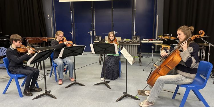 Four young musicians play strings - three violins and one cellow