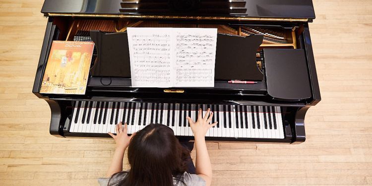 Student sat at a piano. Photograph taken from above their head looking down.