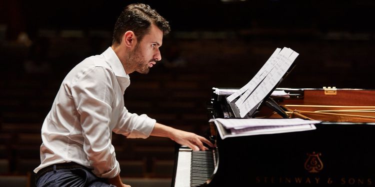 Student playing piano on stage