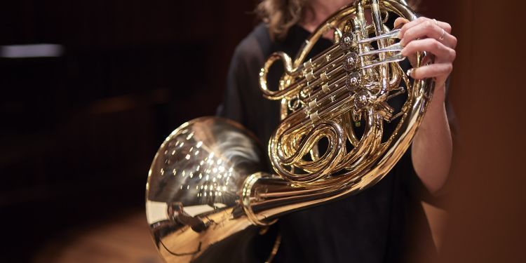 Student on stage playing French horn