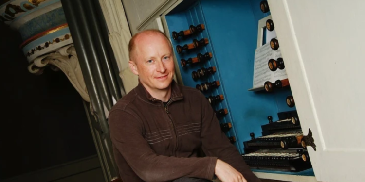 James Johnstone sat on a stool in front of harpsichord