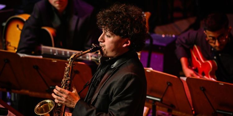 Student playing the saxophone on stage as part of the Jazz ensembles concert