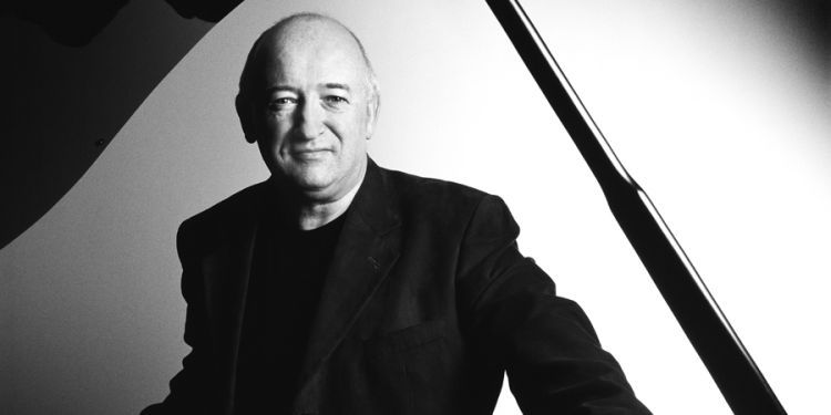 Black and white photo of John O'Conor standing behind a piano