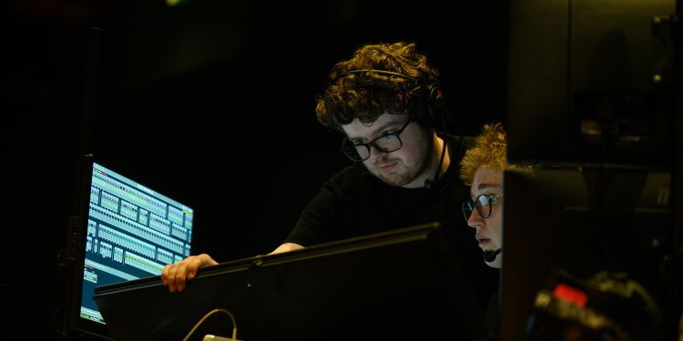 Lighting students looking at screens with headsets on
