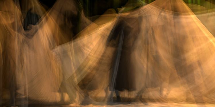 Blurred image showing a blur of white sheets with a black backgrounf