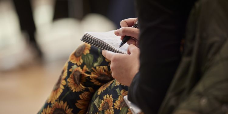 Participant taking notes in a notebook on her lap
