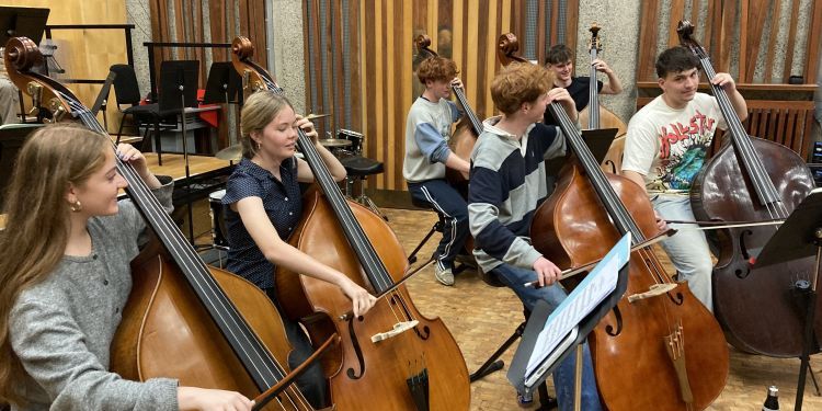 A room of students sat next to one another playing the double bass