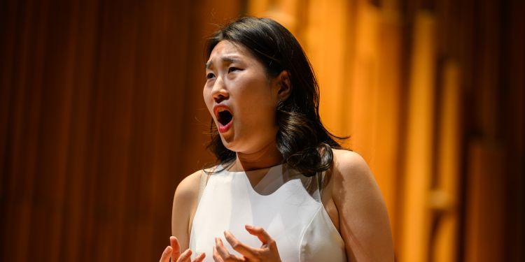 Female presenting vocal student on stage performing looking away from the camera